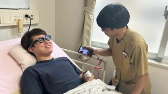 ベッドに横になったままスマートグラス「MiRZA」を装着し、作業療法士の支援を受けて意思疎通を試す。患者役は嶺井第一病院のスタッフ