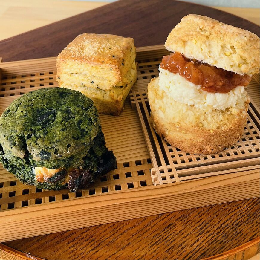 最近は多様な素材を使ったスコーンの人気も高い。写真はトムズスコーンジャパネスクのもの。もちきびとハトムギのプレーン、自家製クロテッドクリームと柿ジャムサンド（右）、宇治抹茶とよもぎ、チョコレート（左）、黒七味とパルメザン（中）（写真：三越提供）