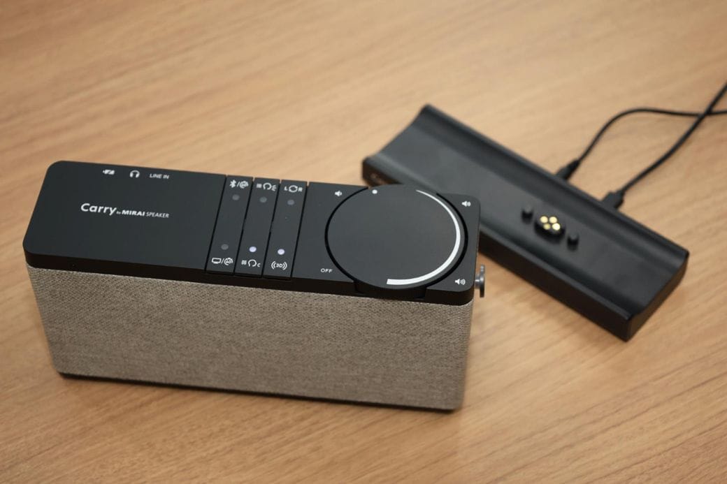 ベースステーションをテレビにつなぐことで、充電・ワイヤレス通信する「キャリー・バイ・ミライスピーカー」（写真：筆者撮影）