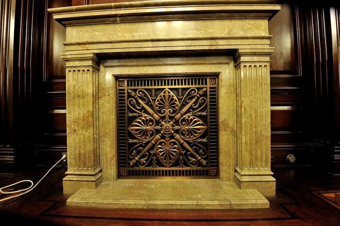 暖炉、マントルピースの焚き口は金属装飾に覆われている