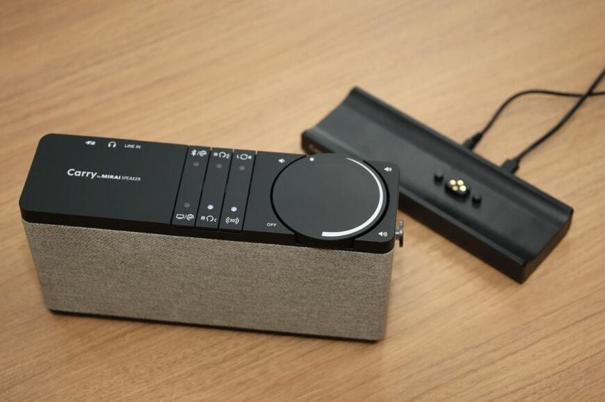 ベースステーションをテレビにつなぐことで、充電・ワイヤレス通信する「キャリー・バイ・ミライスピーカー」（写真：筆者撮影）
