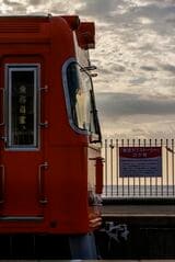 伊予灘を望む高浜線梅津寺駅にミカン色の電車がやってくる。この駅はドラマ『東京ラブストーリー』の聖地だ（撮影：鼠入昌史）