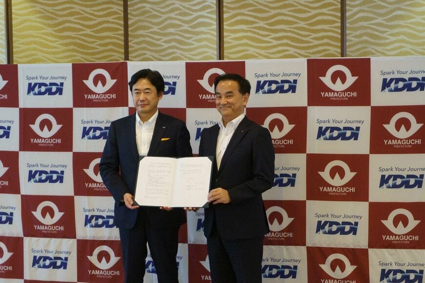 協定書を手にするKDDIの松田浩路社長（左）と山口県の村岡嗣政知事
