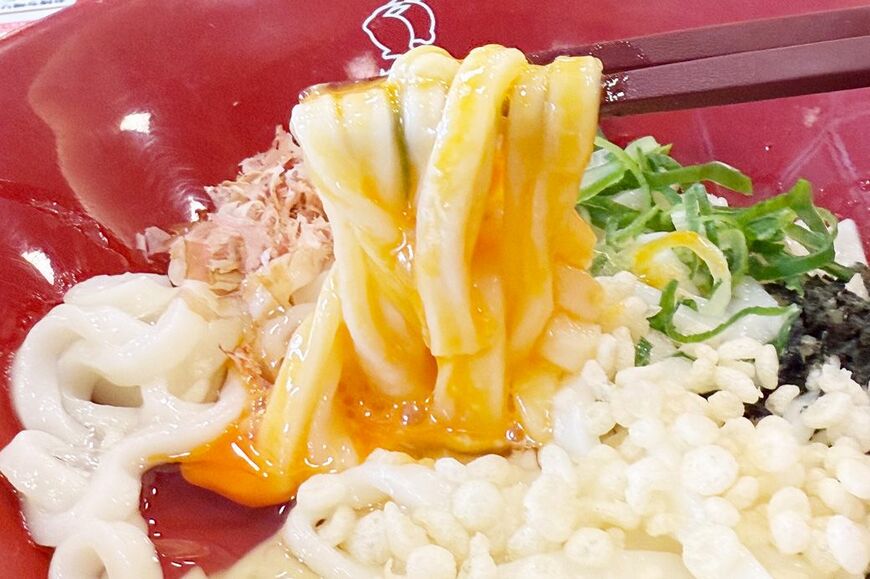 うどんに黄身をからめて召し上がれ。なか卯のうどんは2種類の麺があるのですが、まぜうどんは太い方の麺を使用していました（筆者撮影）