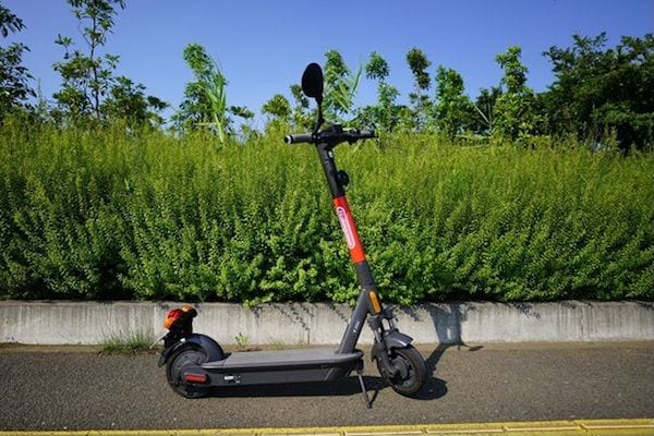 前後にブレーキ、ハンドルの両端にウインカー、高い位置にLEDヘッドライト、衝撃を吸収するサスペンションなどを備えた、千葉県千葉市で実証実験中のシェアリング電動キックボード。料金は10分間の初乗りが100円 、以後1分ごとに15円、30分で合計400円（筆者撮影）