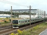 村岡新駅建設予定地付近を走行する東海道線の列車と背後にそびえる「湘南アイパーク」（筆者撮影）