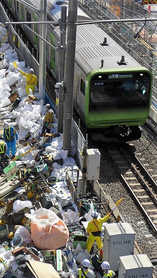 電車の接近時は作業員が旗を振って注意喚起