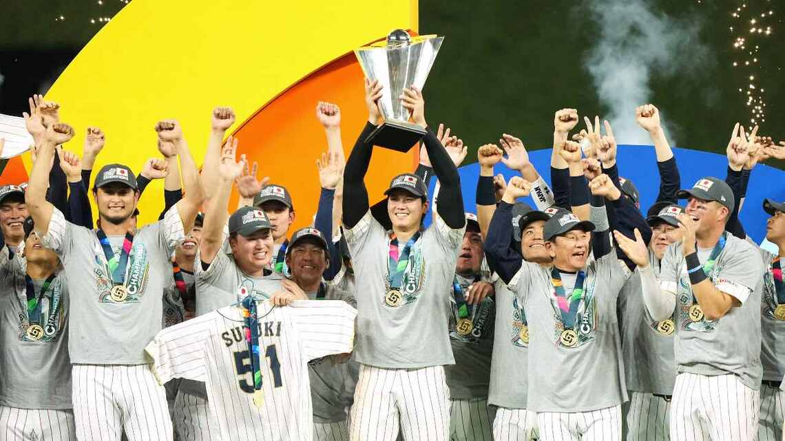 表彰台でWBCの優勝トロフィーを掲げる大谷翔平(中央)をはじめとした日本代表選手たち(写真:時事)