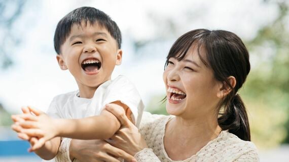 公園で遊ぶ笑顔の男の子と母親