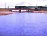 小丸川の鉄橋を渡る日豊本線の貨物列車「ナメクジ」型のシルエットがわかる（撮影：南正時）