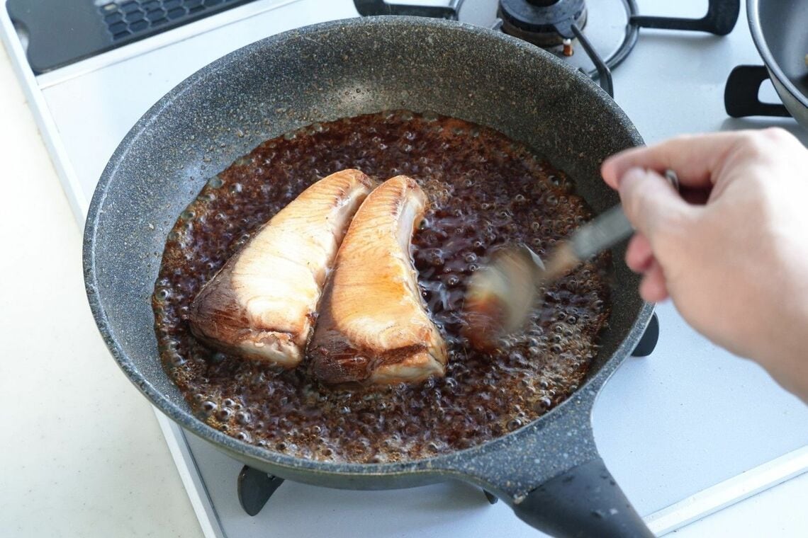 スプーンでブリにたれをかける