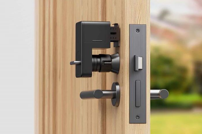SWITCHBOT社のスマートロックは、サムターンをつかむようにして、本体を粘着テープでドアに固定する（写真：SWITCHBOT提供）