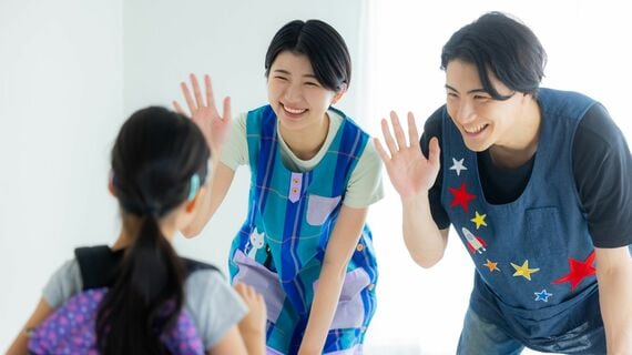 エプロンをした若い男性1人と若い女性1人、リュックを背負った女性の児童