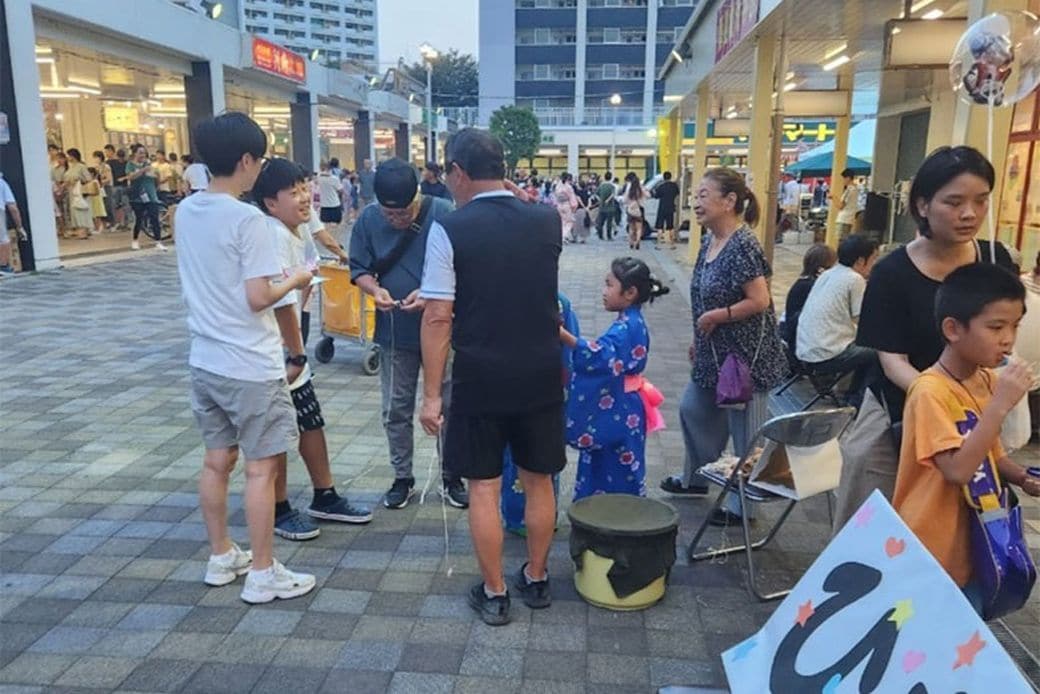 祭りでは、高齢者と団地に暮らす子どもたちとの交流も。芝園かけはしプロジェクトと住人で企画したブースにて、ベーゴマの遊び方を子どもたちに教えて一緒に遊ぶ様子（画像提供／芝園かけはしプロジェクト）
