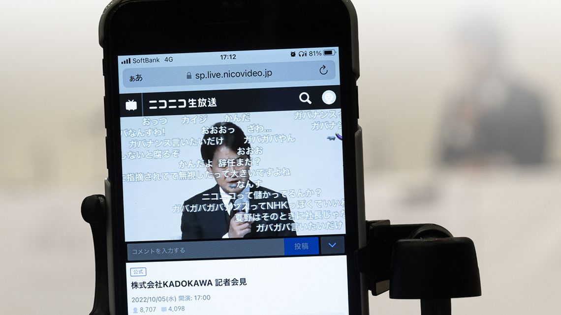 ネット中継されるKADOKAWAの謝罪会見を表示したスマートフォン