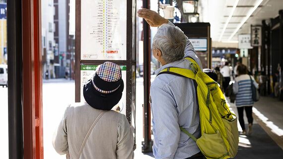 バスの時刻表を確認するシニア夫婦