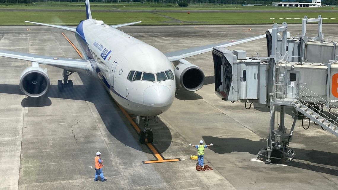 鹿児島空港で機体の誘導をする南国交通のグランドハンドリングスタッフ(記者撮影)