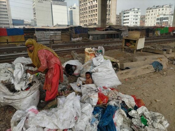 ゴミを漁る女性と、それを待つ子供たち