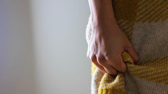 服を握った人物の手元