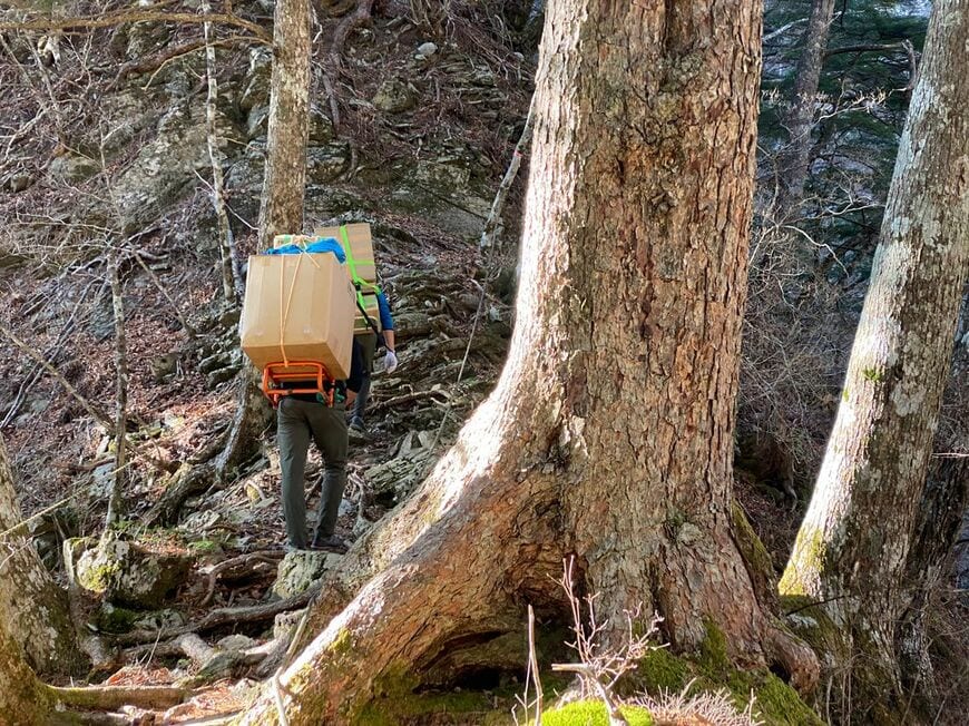 大きな荷物を背負って山道を登る「歩荷」たち（写真：松見さん提供）