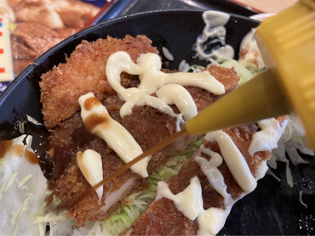 ソースチキンカツ丼にソースをかける様子
