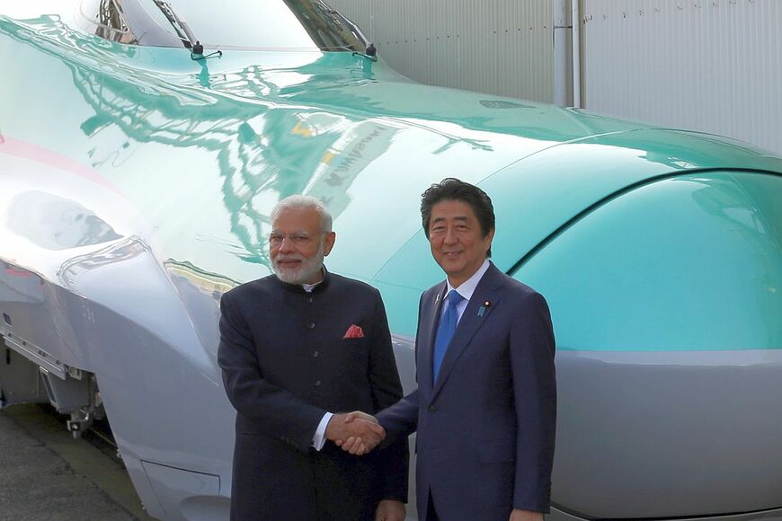 川崎重工業の工場で製造中のE5系新幹線の前で握手するインドのモディ首相と安倍晋三首相（当時）＝2016年11月（写真：Bloomberg）