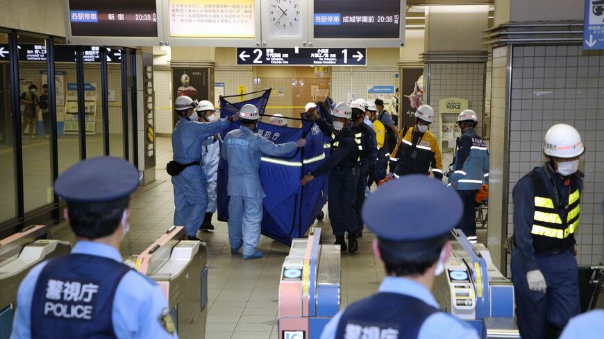 小田急線祖師ケ谷大蔵駅から負傷者を運び出す救急隊員ら（奥）＝8月6日（写真：時事）