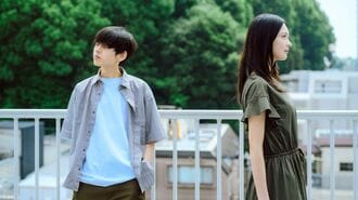 緑を背景に背を向け立つ若い男女