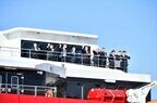 船上のデッキから手を振る関係者ら