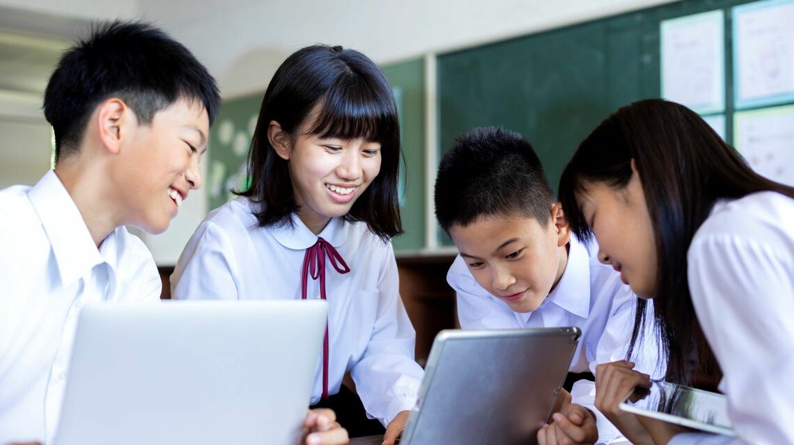 端末を前に笑顔で話し合う学生たち