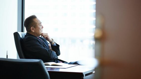 椅子に座り外を眺める重役の男性
