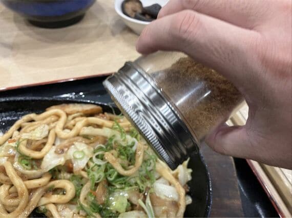 焼きうどんにふりかけをかける様子