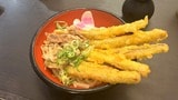 ごぼうの天ぷらをのせたうどんは人気商品。北九州名物のかしわ（鶏肉）を甘辛く煮付けたトッピングもある（記者撮影）