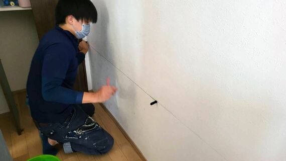 建築業者が壁内部を診断してカットする位置にラインを引いている