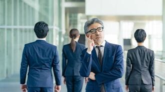 部下に背を向けて悩む上司の男性