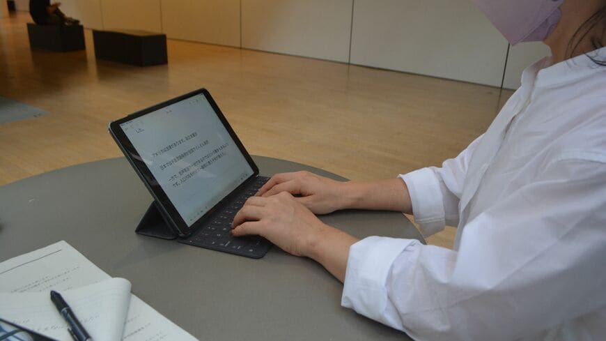 『障害と、学識における「才能」の組み合わせは、とても生きづらいと思います』。先天性の難聴で、のちにIQ130台だとわかった40代女性に話を聞いた（タブレットで質問に答える女性／©朝日新聞社）