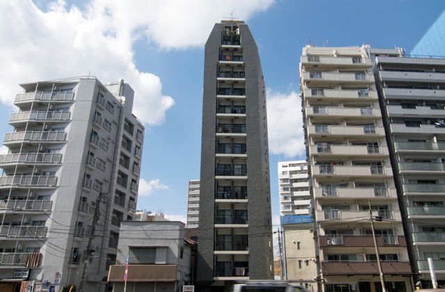 都内の投資用マンション（中央）。用地費を抑えるため、狭小な土地に細長く建つ例が多い（記者撮影）