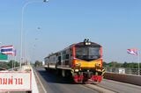 国境の併用橋を行く国際列車。列車の左右にタイとラオスの国旗（写真：谷川一巳）