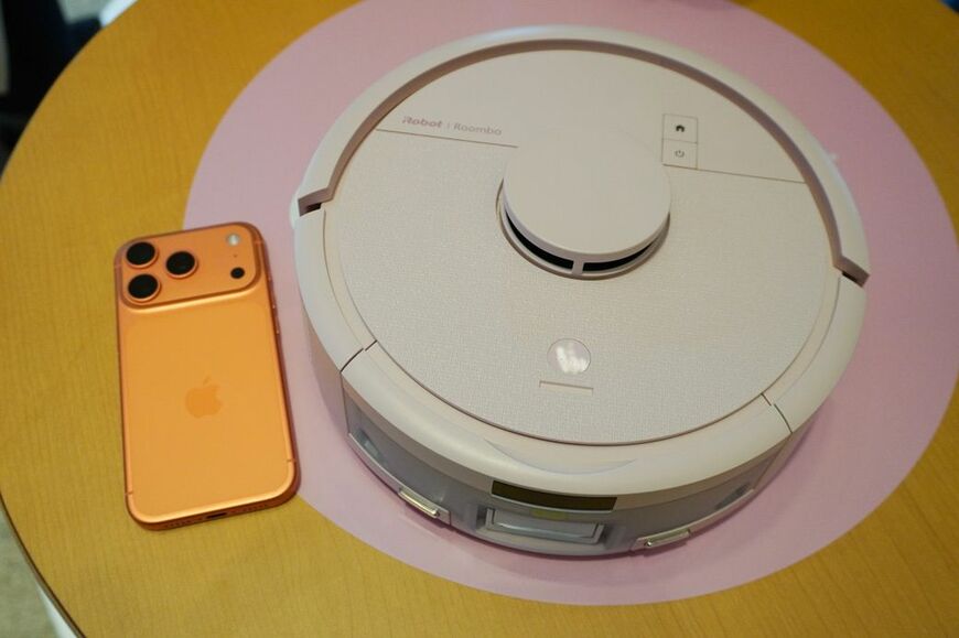 ルンバ ミニとスマートフォンを並べたところ。本体直径は24.5cmで、従来モデルから約10cm小さくなった（写真：筆者撮影）