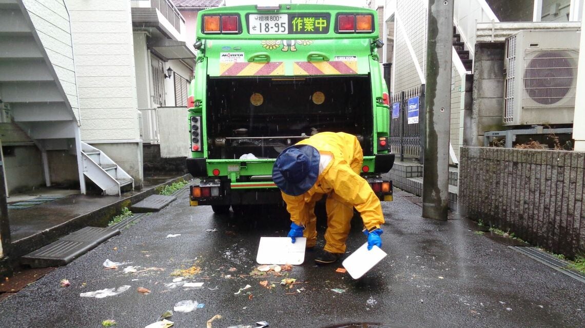 カラスに荒らされて散乱したごみを集める様子（筆者撮影）