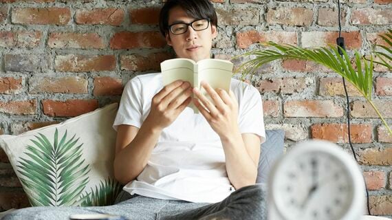 読書をする男性と7時を指す時計