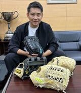 松坂恭平さんは自社で手がけたグラブ「ONE OF THE ANSWER」を手にした。机上の左が今季ソフトバンク柳田が使用、手前が巨人松田が使用したモデル（撮影：久我悟）