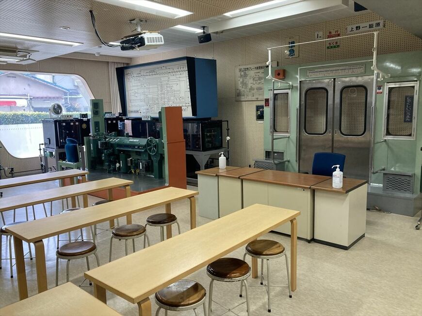 実物の電車のドアや信号、「進路制御卓」などが並ぶ昭和鉄道高校の実習室（筆者撮影）