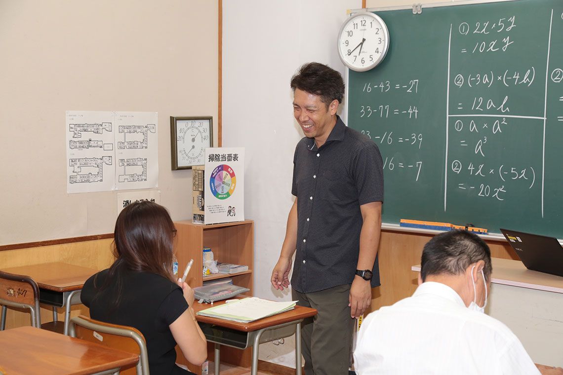 生徒の質問に笑顔を見せる教員