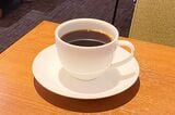 そっけないほどシンプルな、ロゴなしのカップ&ソーサーに、琥珀色のホットコーヒー（筆者撮影）
