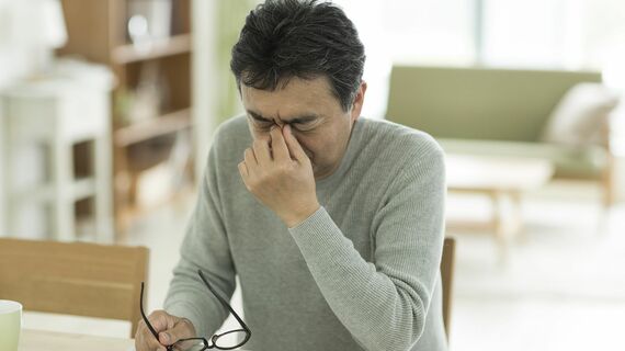 目元を押さえる男性
