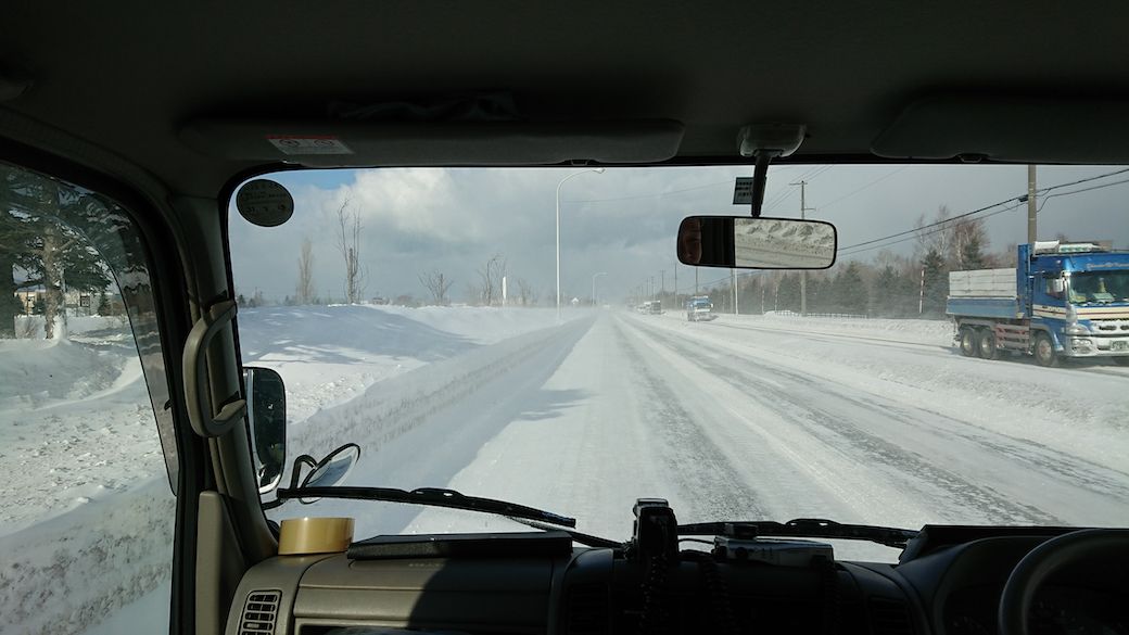 除雪による雪山が道の両側にでき、3車線の道が2車線となっている雪道のなか収集に向かう（筆者撮影）