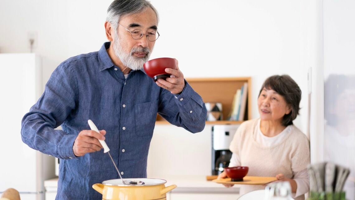 味噌汁の味見をするシニア夫婦