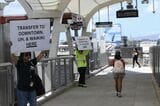 ラグーンドライブ駅で、パネルを掲げてダウンタウンやワイキキ方面へのバス乗り継ぎ客を誘導するスタッフ（記者撮影）