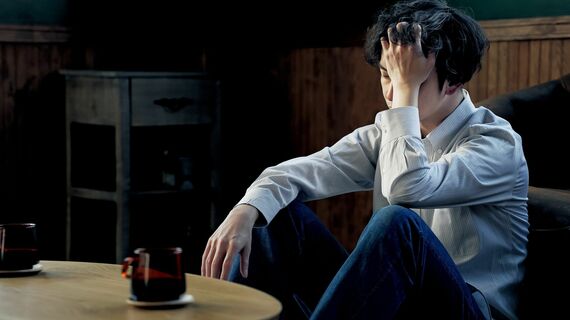 落ち込んで一人で頭を抱える男性